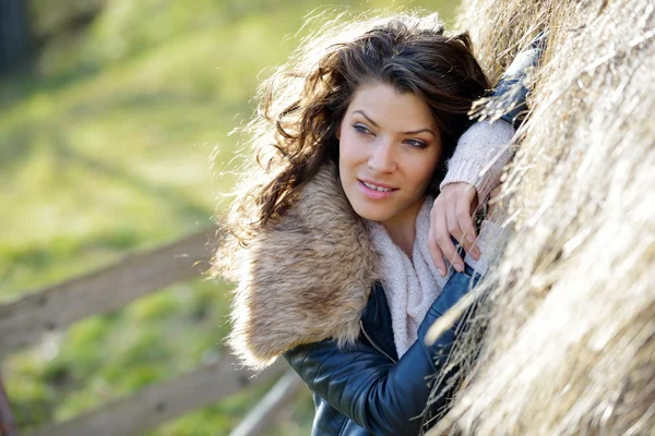 Mooie jonge vrouw ontspannen onder een stapel hooi in de herfst — Stockfoto