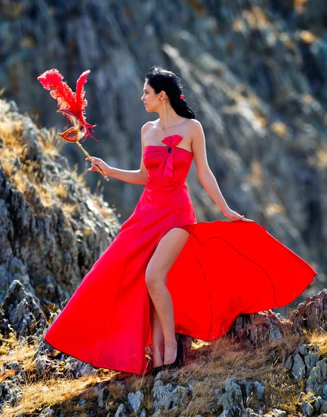 Mujer joven con vestido rojo largo y máscara — Foto de Stock