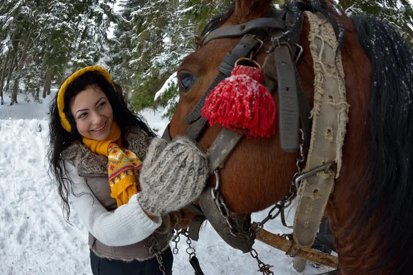 Vacker brunett kvinna stående med häst på vintern — Stockfoto