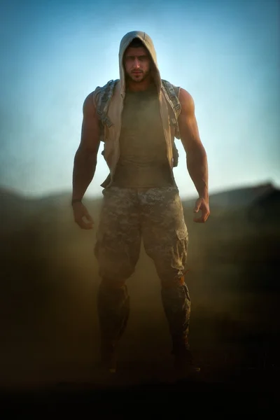 Athletic young man on dusty field — Stock Photo, Image