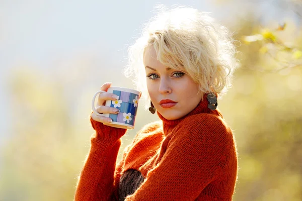 Mujer joven sosteniendo la taza de té al aire libre —  Fotos de Stock