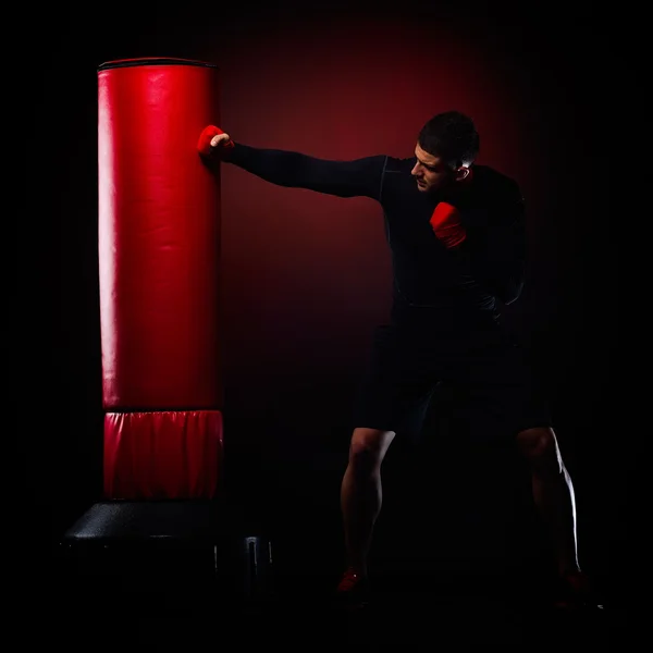 Fiatal férfi állt boksz zsák stúdió — Stock Fotó