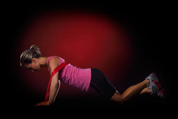 Jonge vrouw uitoefenend met elastische fitness band in de sportschool — Stockfoto