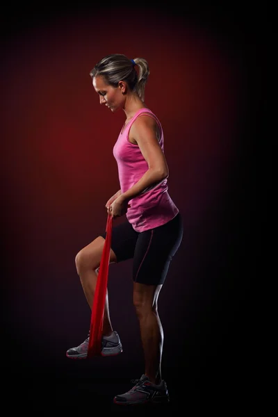 Jovem mulher se exercitando com faixa de fitness elástica no ginásio — Fotografia de Stock