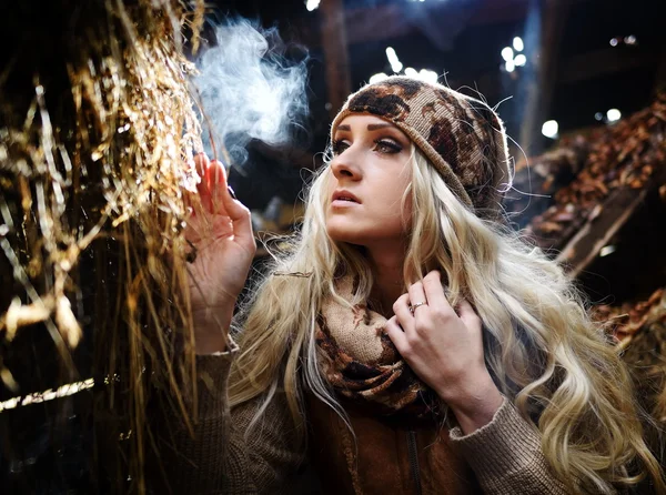 Vacker kvinna avkopplande i halm på hösten i rökig, dammiga rum — Stockfoto