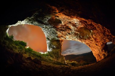 Bir mağara girişi görülen yıldız dolu gece gökyüzü