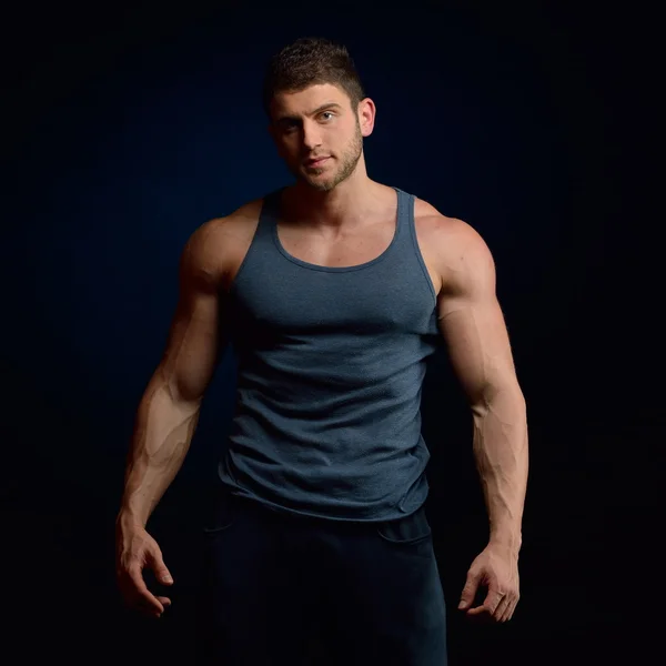 Athletic young man portrait in studio with dark background — Stock Photo, Image