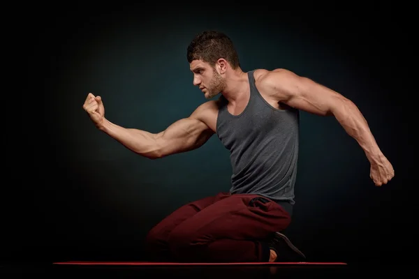 Atletische jongeman portret in studio met donkere achtergrond — Stockfoto