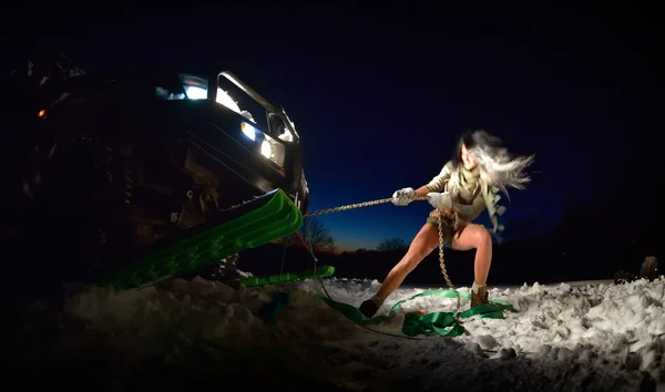 Νέα αθλητικά γυναίκα τραβώντας το αυτοκίνητο το χειμώνα — Φωτογραφία Αρχείου