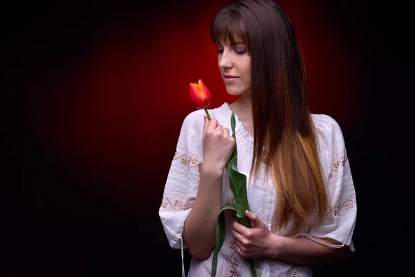 Ung vacker kvinna med röd tulpan i studio — Stockfoto