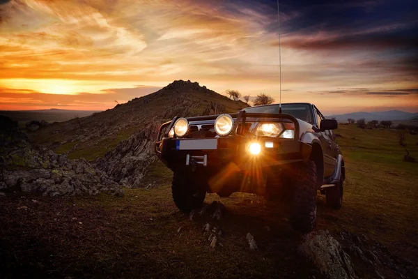 Offroad auto op bergweg bij zonsondergang — Stockfoto