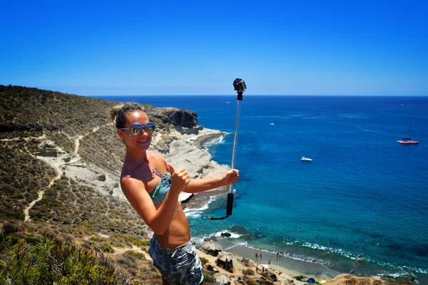 Jeune femme sur la plage en été en utilisant gopro — Photo