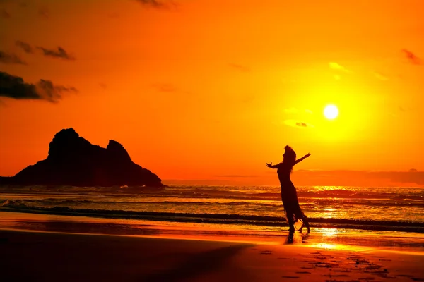 Silueta de mujer joven en la playa en verano la luz del atardecer — Foto de Stock