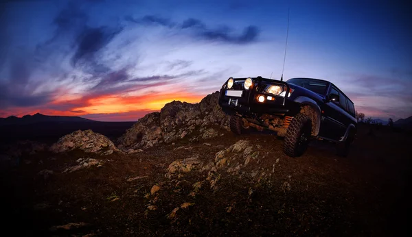 Offroad carro na estrada da montanha ao pôr do sol Imagens Royalty-Free