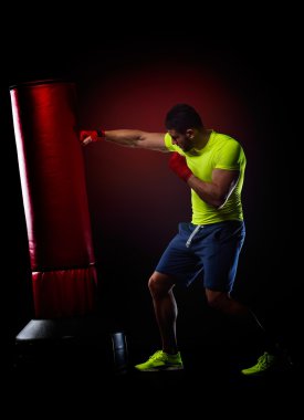 young man standing exercising with  boxing bag in studio clipart