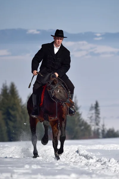 Молодой человек верхом на лошади на открытом воздухе зимой — стоковое фото