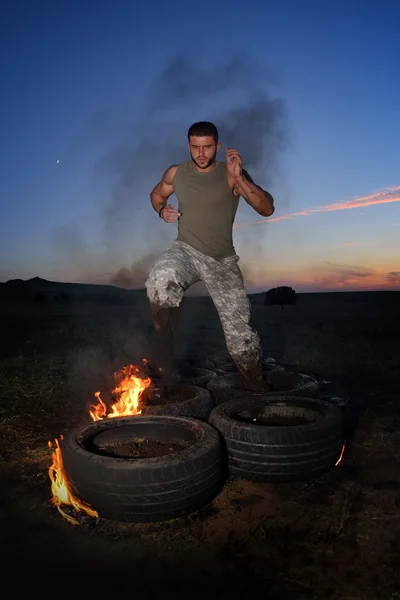 Athletic young man exercising on dusty field — Stock Photo, Image