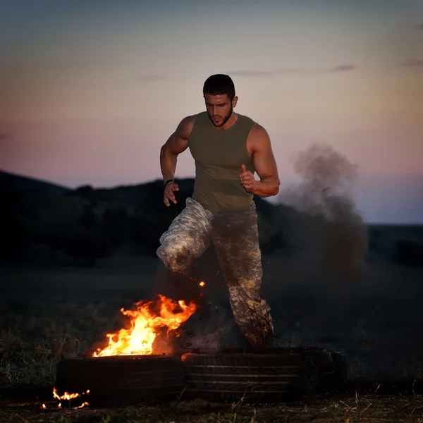 Athletic young man exercising on dusty field — Stock Photo, Image