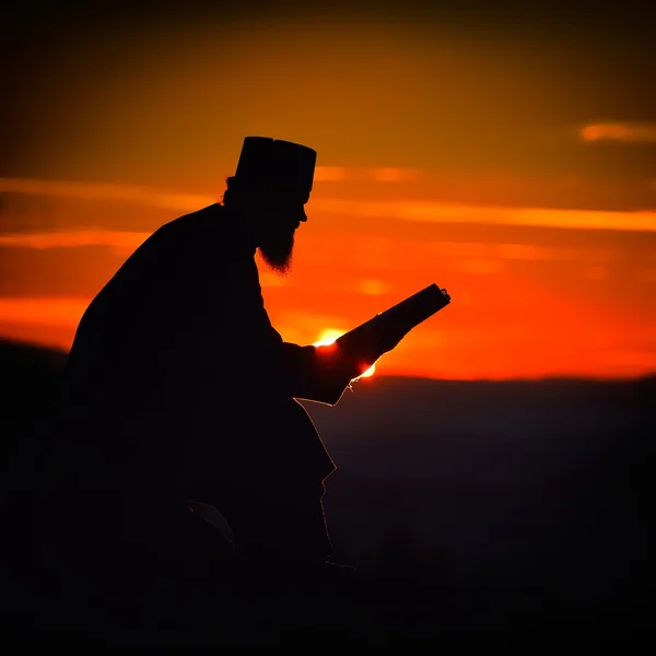 Silhouet van priester lezen in de zonsondergang licht, Roemenië, Ceahl — Stockfoto