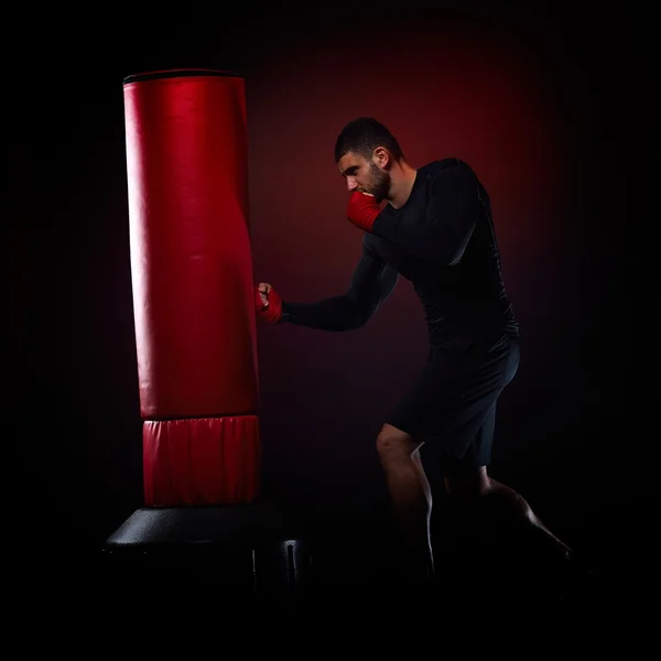Fiatal férfi állandó gyakorlása boksz zsák stúdió — Stock Fotó