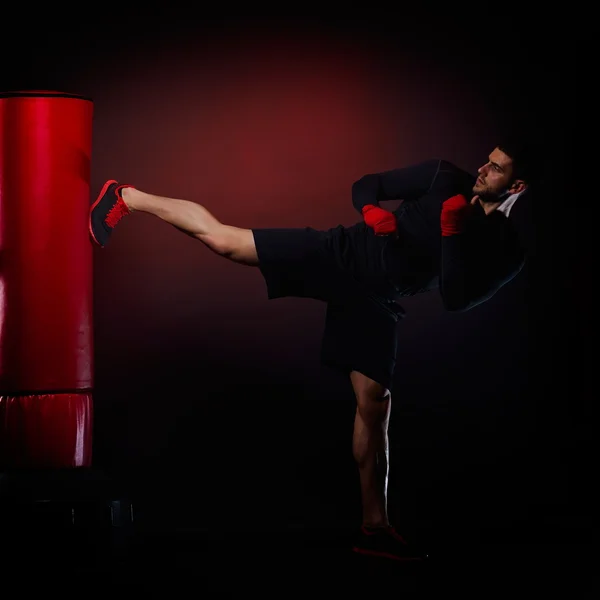 Ung man utövar väska boxning i studio — Stockfoto
