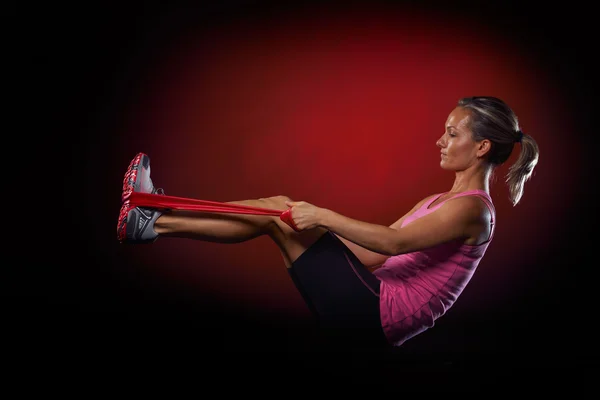 Jovem mulher se exercitando com faixa de fitness elástica no ginásio — Fotografia de Stock