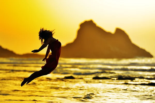 Jonge vrouw springen op het strand in de zomer 's avonds — Stockfoto