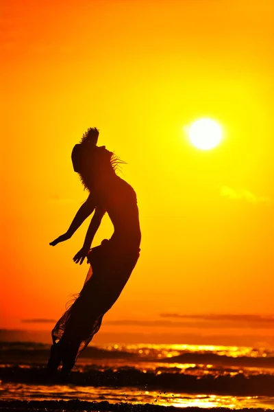 Young woman jumping on the beach in summer evening — Stock Photo, Image