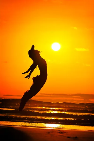 Young woman jumping on the beach in summer evening — Stock Photo, Image