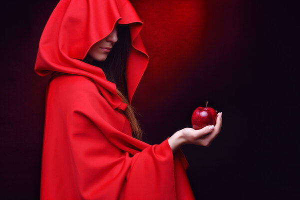 Beautiful woman with red cloak holding apple in her hand