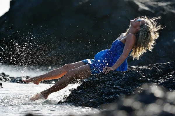 Žena sedí na skalnaté pláži — Stock fotografie