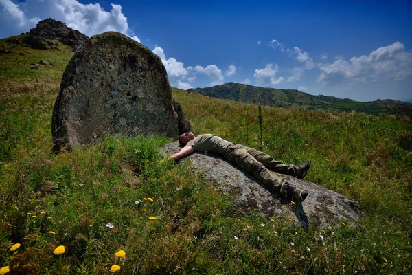 Männlicher Tourist ruht sich auf großem Stein aus — Stockfoto