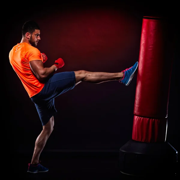 Jovem homem exercitando saco de boxe no estúdio — Fotografia de Stock