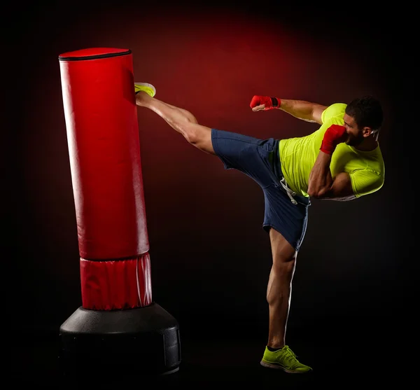 Jovem homem exercitando saco de boxe — Fotografia de Stock