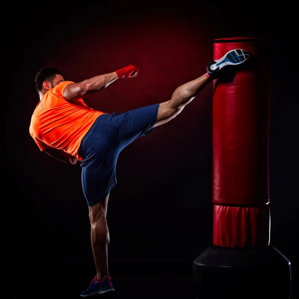 Joven hombre ejercitando bolsa de boxeo en estudio — Foto de Stock