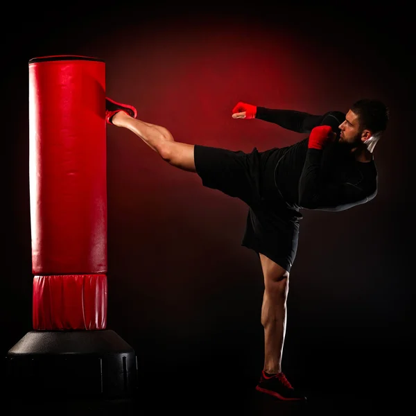 Jovem homem exercitando saco de boxe — Fotografia de Stock