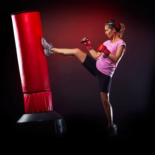 Jovem mulher exercitando saco de boxe no estúdio — Fotografia de Stock