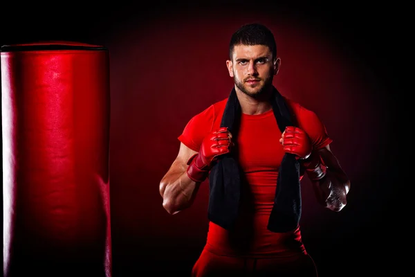 Young man standing by  bag boxing in studio — Stock Photo, Image