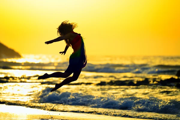 Jonge vrouw springen op het strand in de zomer 's avonds — Stockfoto