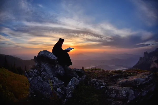 Silhouette del sacerdote che legge alla luce del tramonto, Romania, Ceahl — Foto Stock