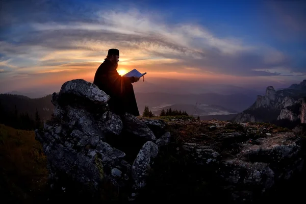 Siluetă de lectură preot în lumina apusului de soare, România, Ceahl — Fotografie, imagine de stoc