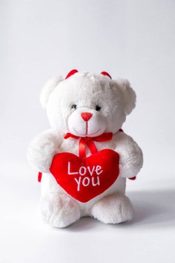Beyaz arka planda kalbi olan oyuncak ayı.