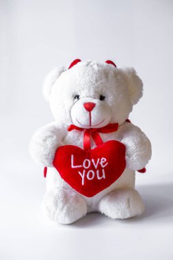 Beyaz arka planda kalbi olan oyuncak ayı.