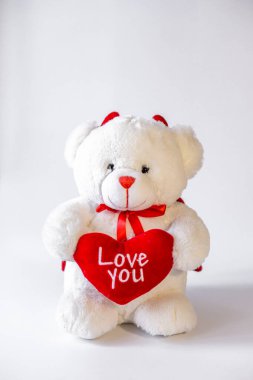 Beyaz arka planda kalbi olan oyuncak ayı.
