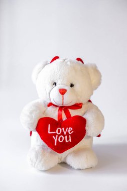 Beyaz arka planda kalbi olan oyuncak ayı.