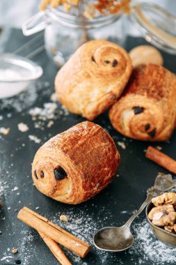 Tahta arka planda çikolata parçalı tatlı. Çikolatayla sarılmış poğaça turtası.