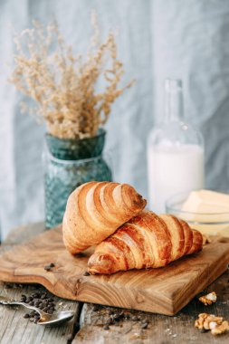 Kahvaltıda kruvasan ve süt. Ahşap bir masada taze pişmiş kruvasan..