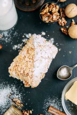 Yakın plan şekerli Napolyon keki. Napolyon keki, siyah taş bir tahtanın üzerinde malzemeler var..