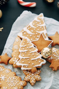 Koyu arkaplanda zencefilli kurabiye ve koni kompozisyonu. Kurabiyeli ve noel ağaçlı yassı bir ev..