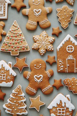 Ev şeklinde kurabiyeler, Noel ağacı, bir insan, kremayla süslenmiş bir yıldız. Kış tatili şablonu, zencefilli çörek seti, desenlerin düzeni..